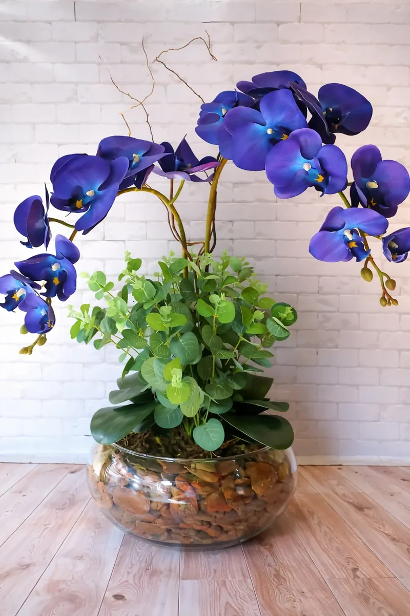 Arranjo de orquideas azuis em vaso de vidro com pedras