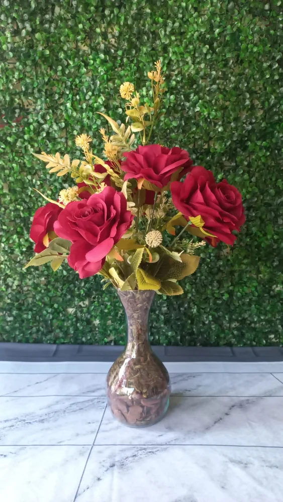 Arranjo de rosas vermelhas com folhagem dourada em vaso bronze